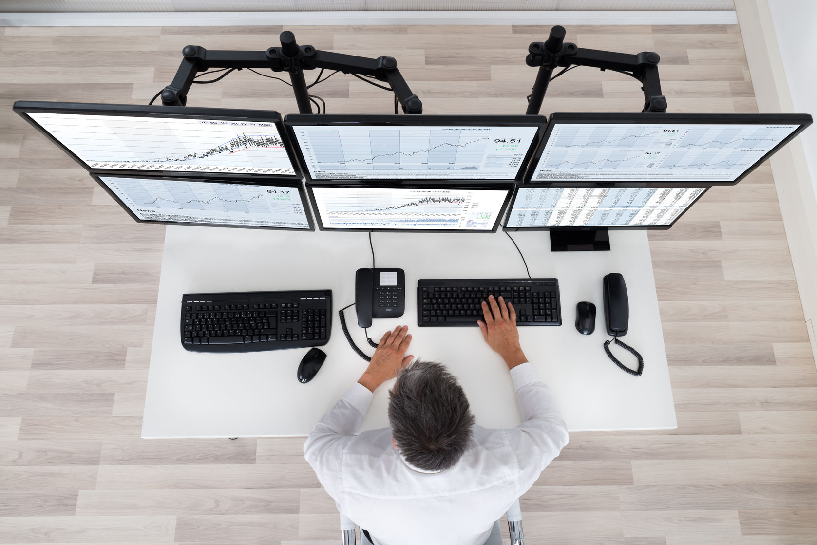 rear view of stock market broker looking at graphs at desk in office